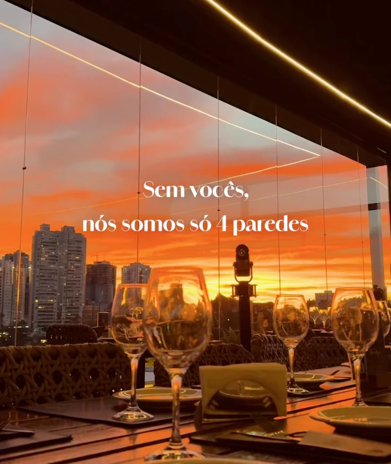 Reel de restaurante rooftop: taças na mesa com o pôr do sol ao fundo